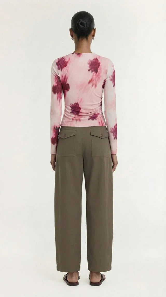 Woman wearing a pink tie-dye long sleeve top and olive green wide-leg trousers.