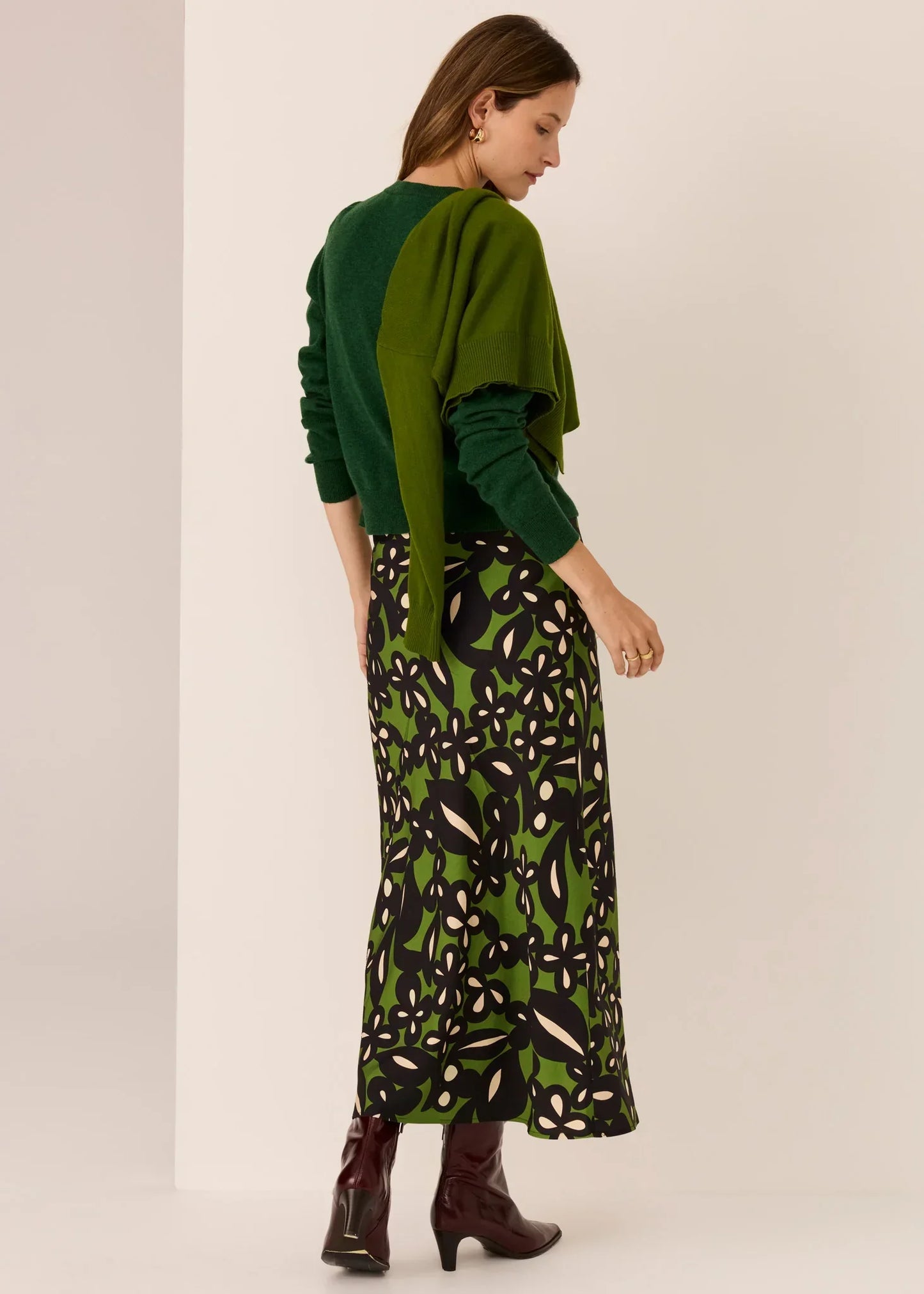 Woman in green floral midi skirt, colorblock sweater, and burgundy boots — women's fashion