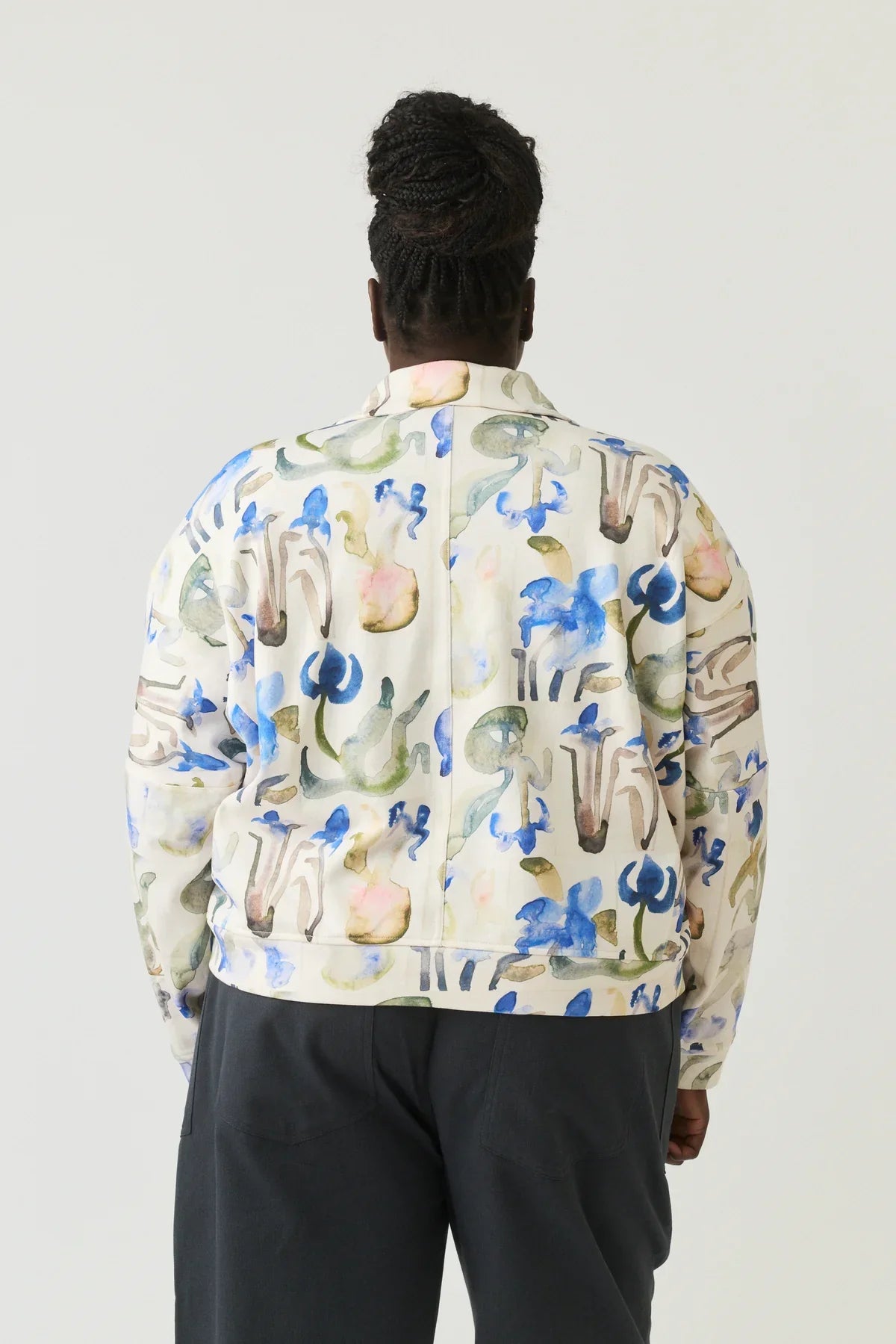 Back view of woman wearing a watercolor floral print jacket and dark pants