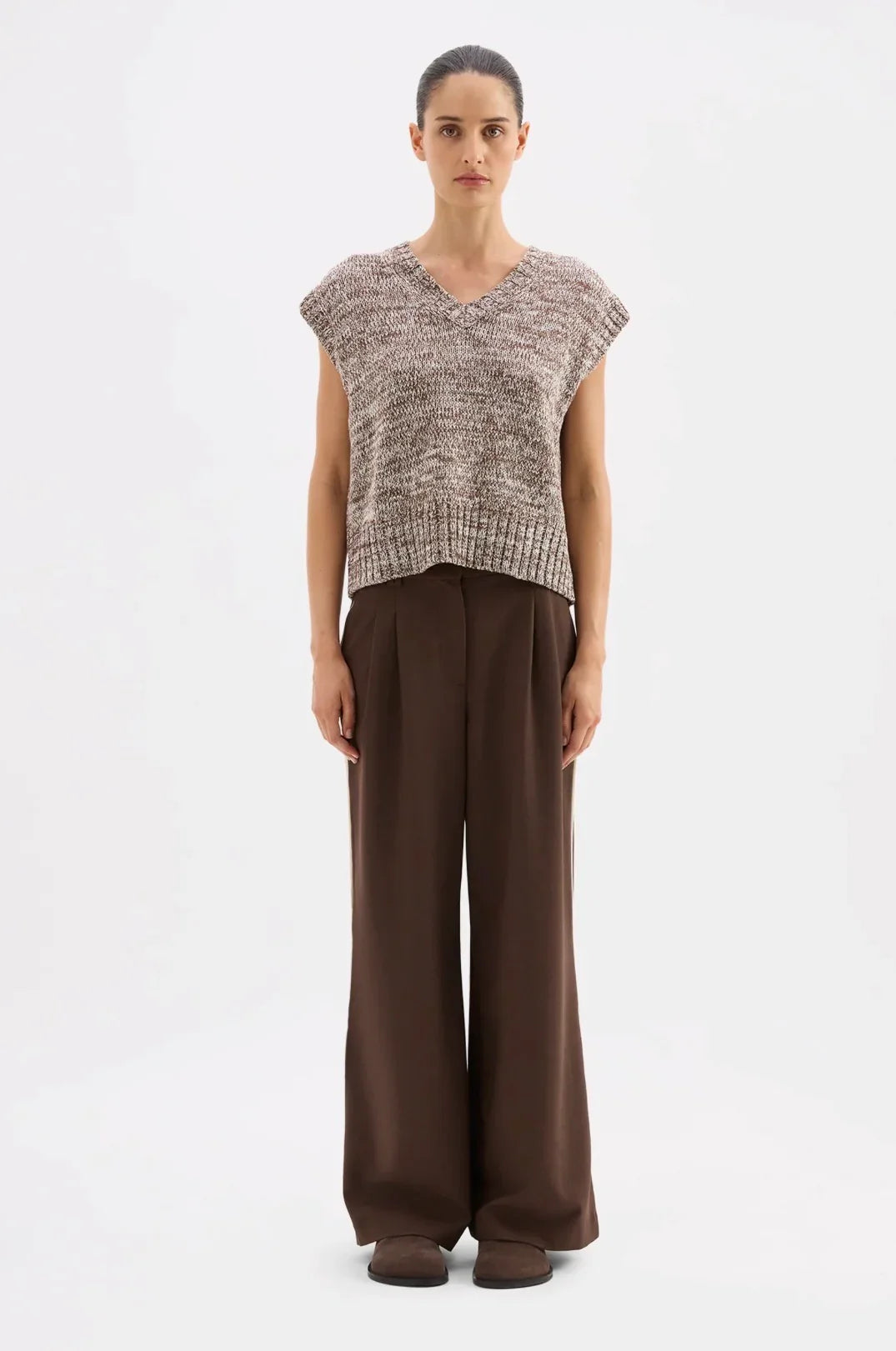 Woman wearing textured V-neck sleeveless knit top with wide-leg brown trousers, modern women's fashion