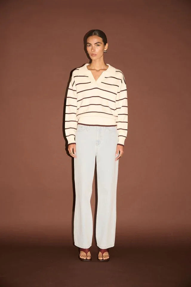 Woman wearing striped V-neck sweater and light wash wide-leg jeans, casual chic outfit