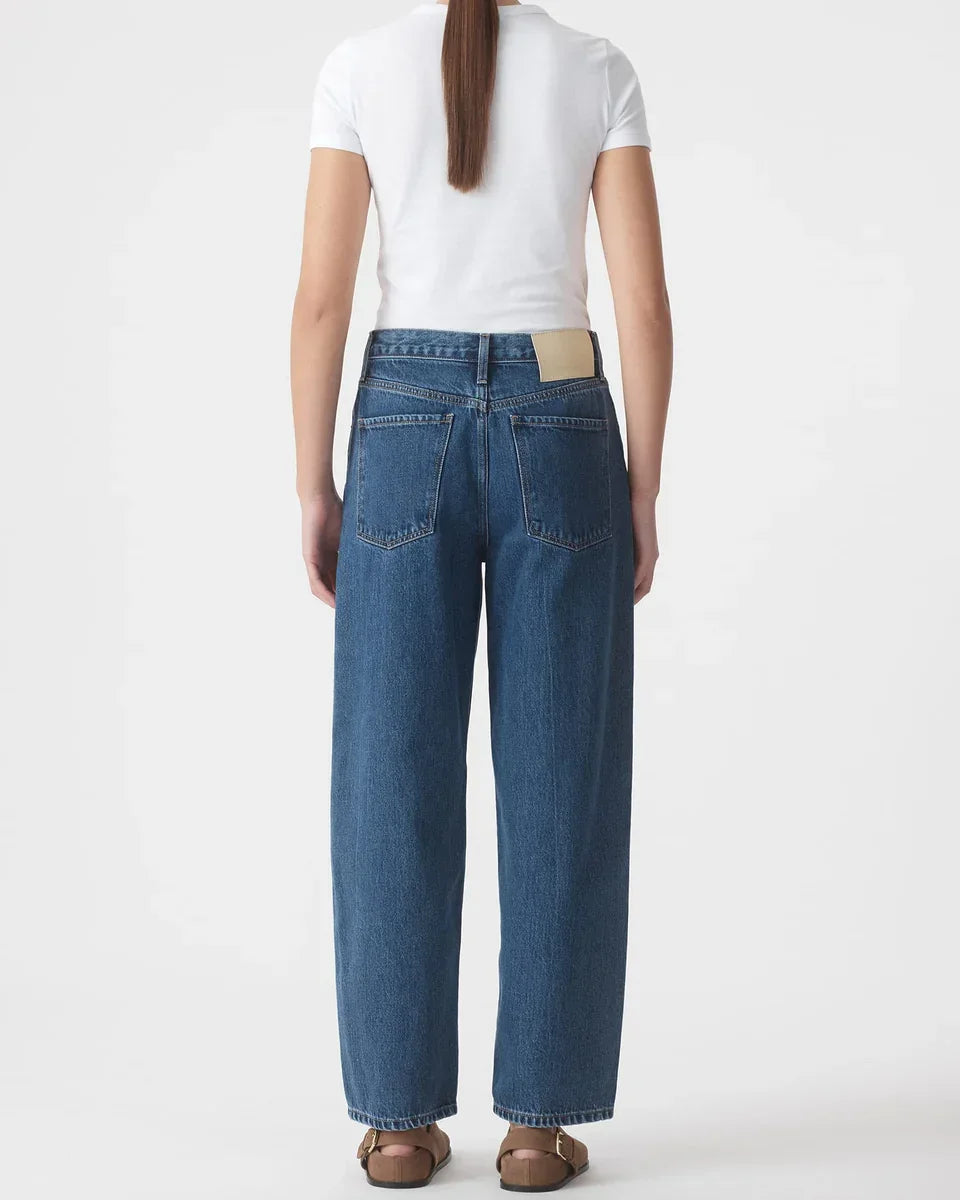 Wide-leg denim jeans with back pockets, paired with white tee and brown sandals
