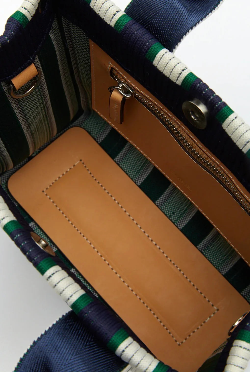 Tartan-patterned tote bag interior with tan leather zipper pocket and striped handles