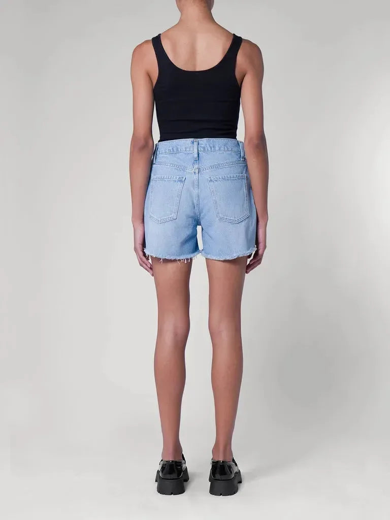 Light blue denim shorts with frayed hem, paired with black tank top and chunky loafers