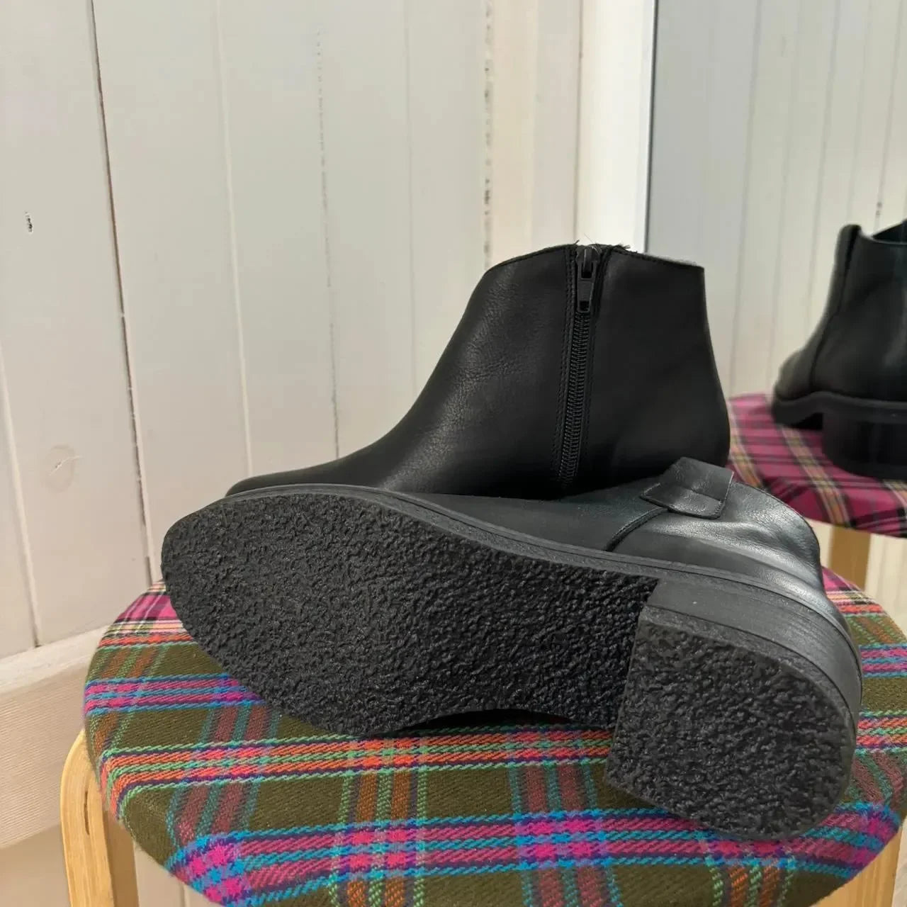 Black leather ankle boots with side zipper, displayed on plaid stool, women's fashion footwear