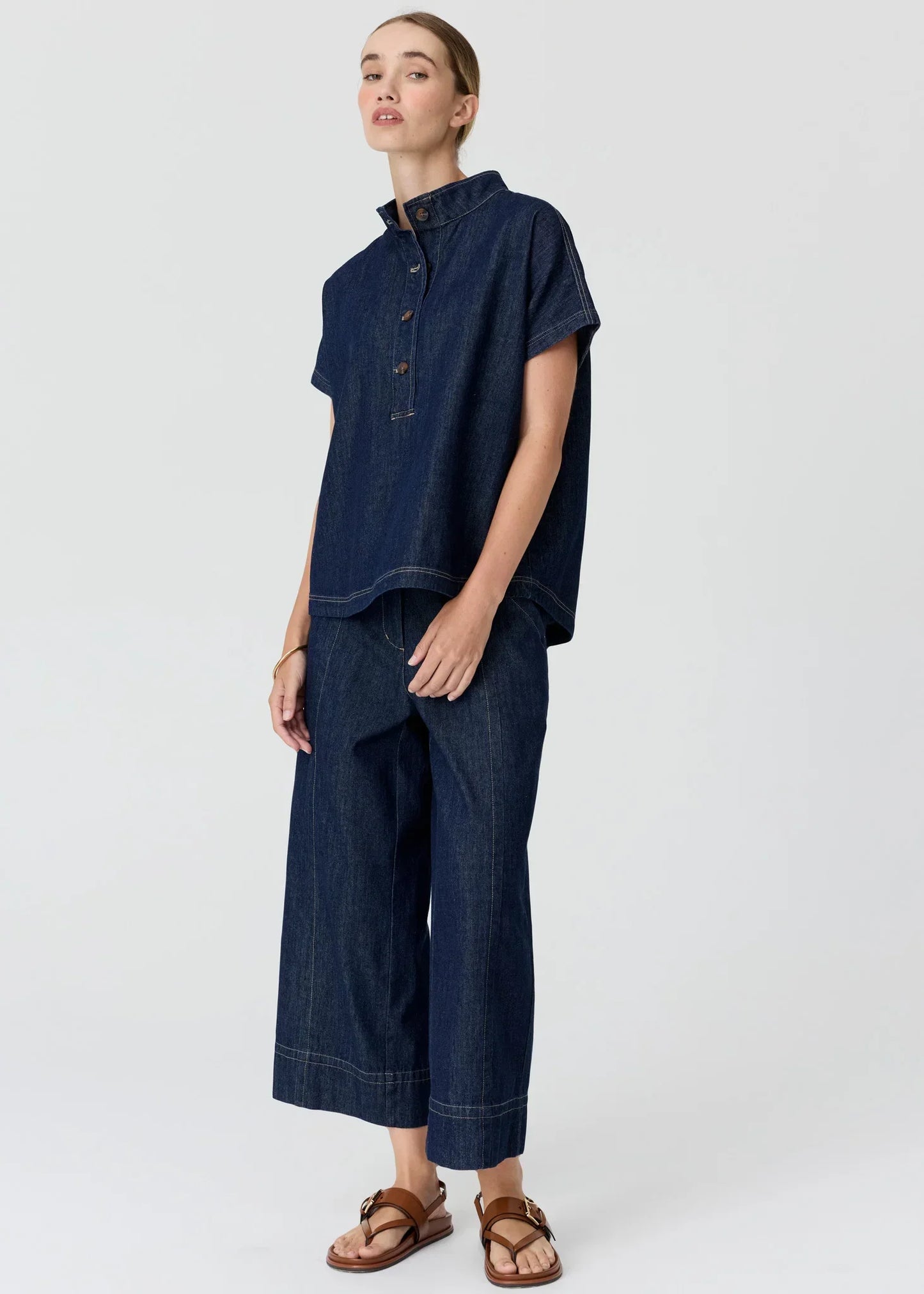 Woman wearing a dark blue denim short-sleeved shirt and matching wide-leg trousers.