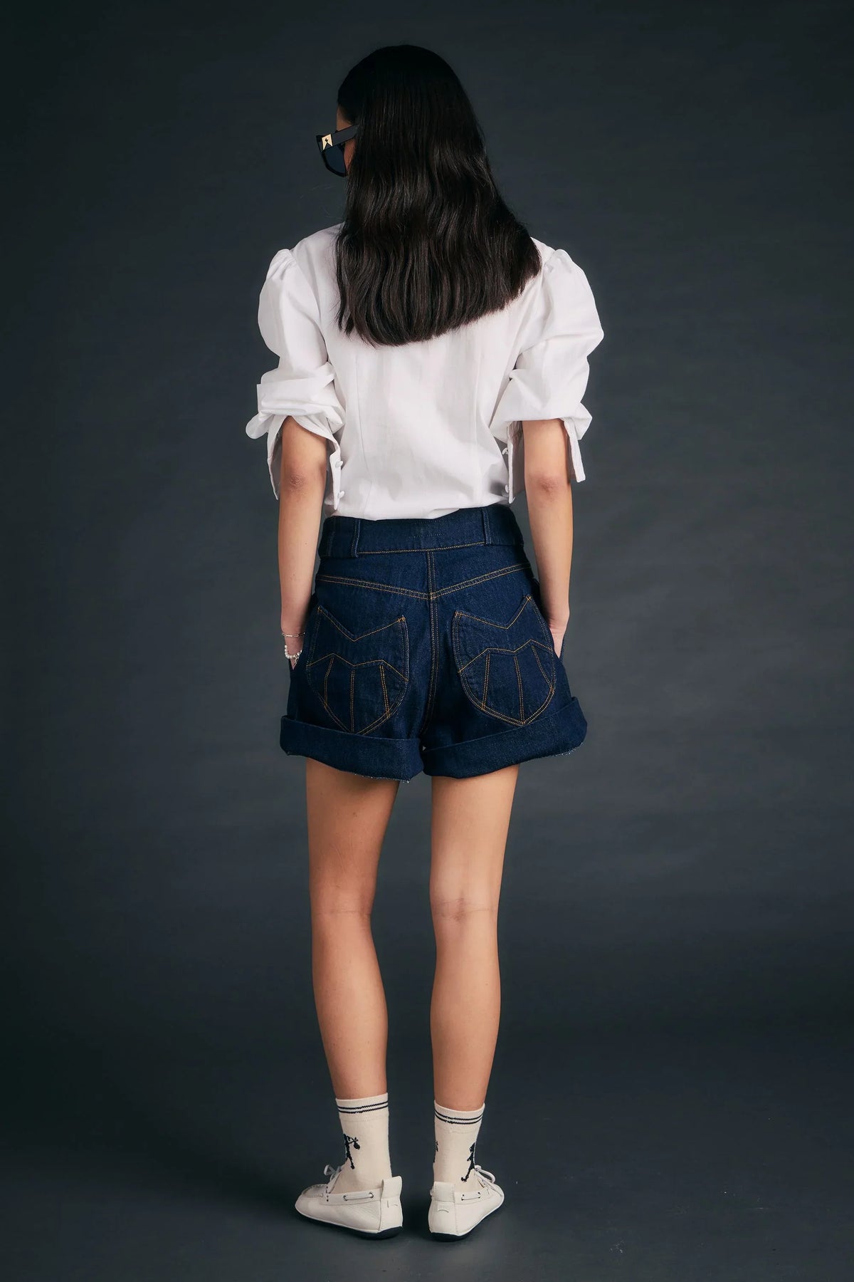 Back view of a person wearing Outland Denim X Karen Walker Starboard Shorts and a white blouse.