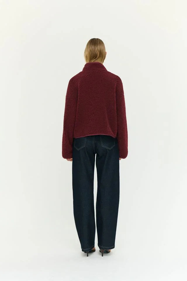 Woman wearing burgundy fuzzy cropped sweater and wide-leg dark jeans, back view