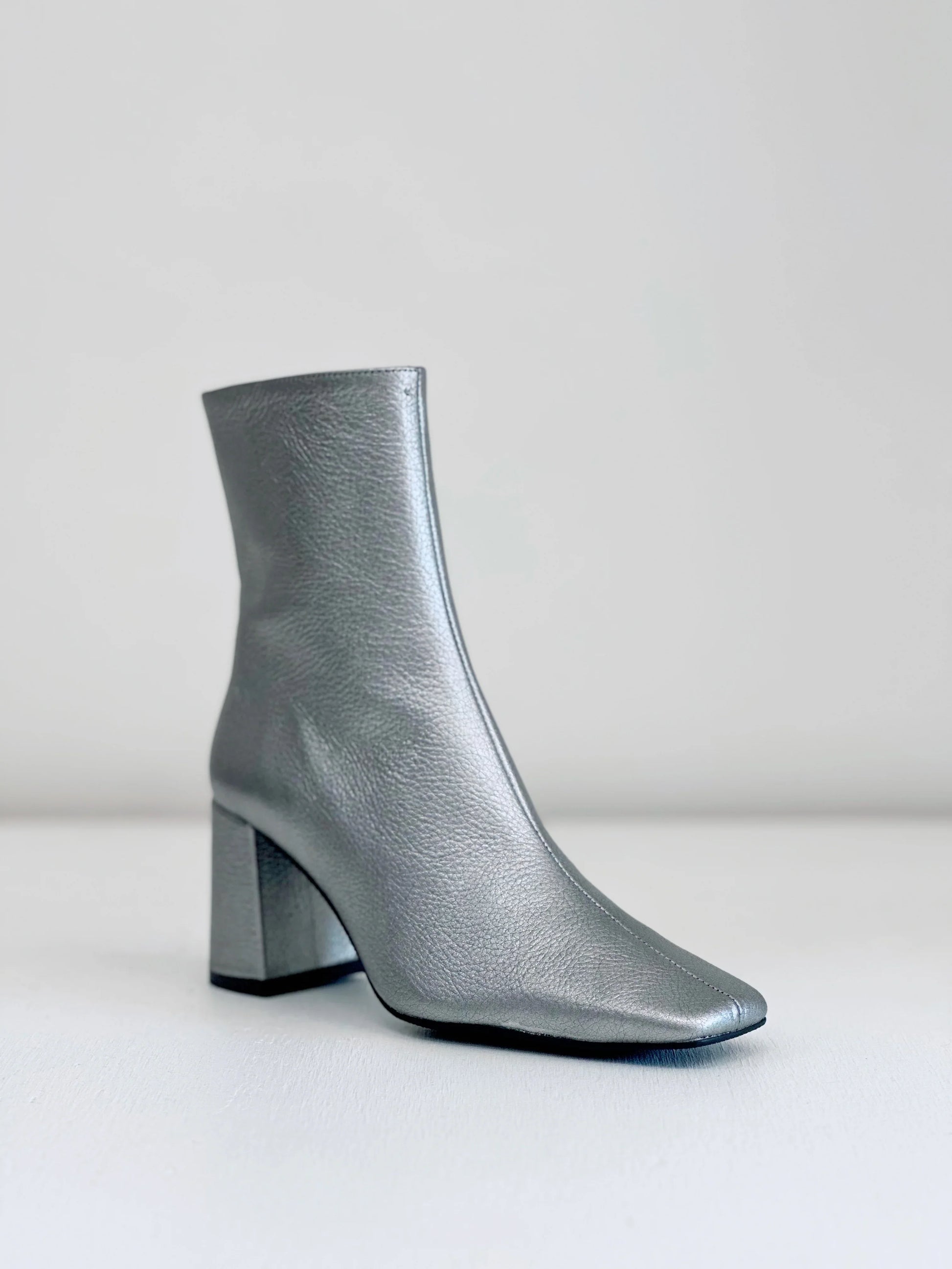 Silver leather ankle boot with block heel and square toe on light background
