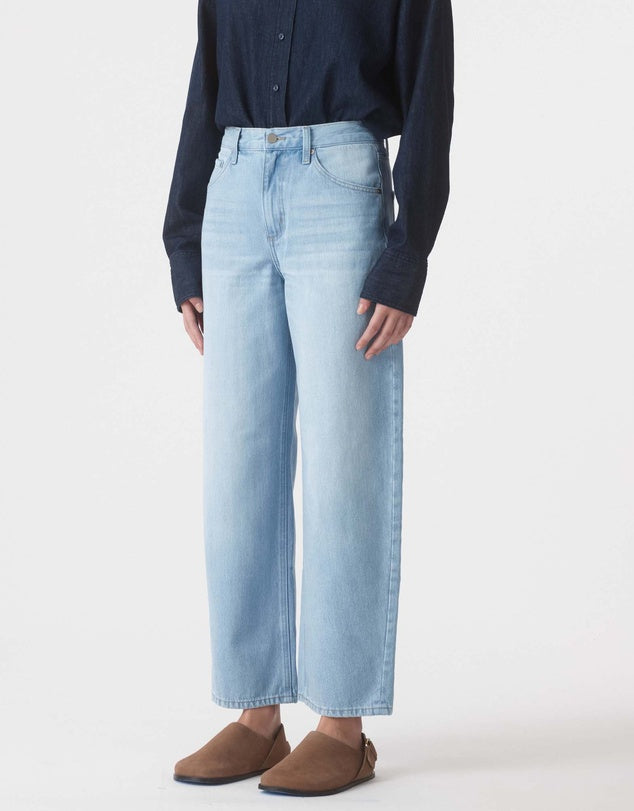 Person wearing light blue jeans and a dark shirt on a white background