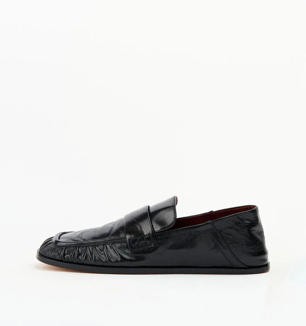 Black leather women's loafer with textured details on white background