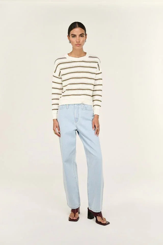 Woman wearing striped knit sweater, light blue jeans, and brown block heel sandals
