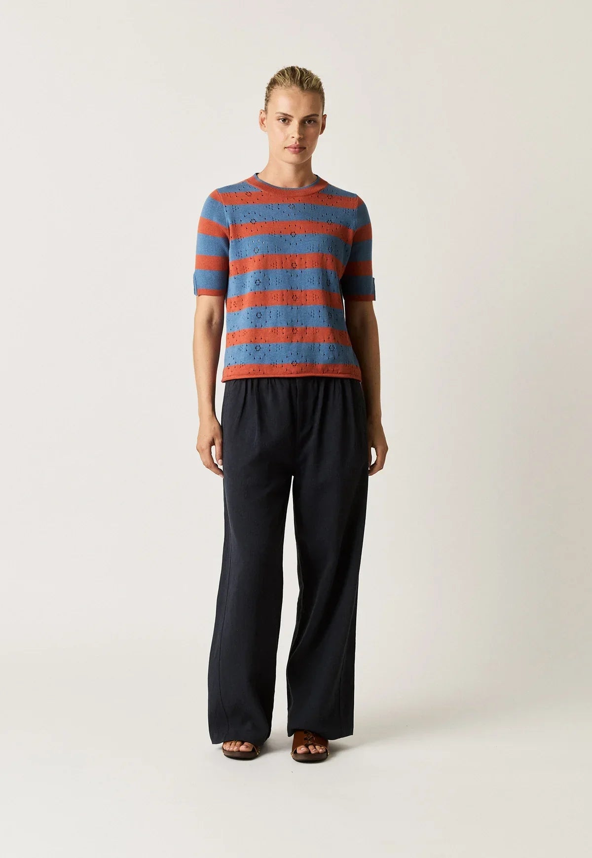 Woman wearing NANCYBIRD Rana Knit Tee in Terracotta Stripe and navy wide-leg trousers.