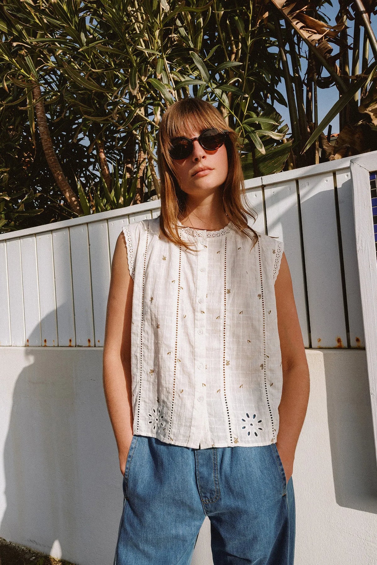 Woman wearing an INDI & COLD Stamp Print Sleeveless Shirt and blue jeans outdoors.