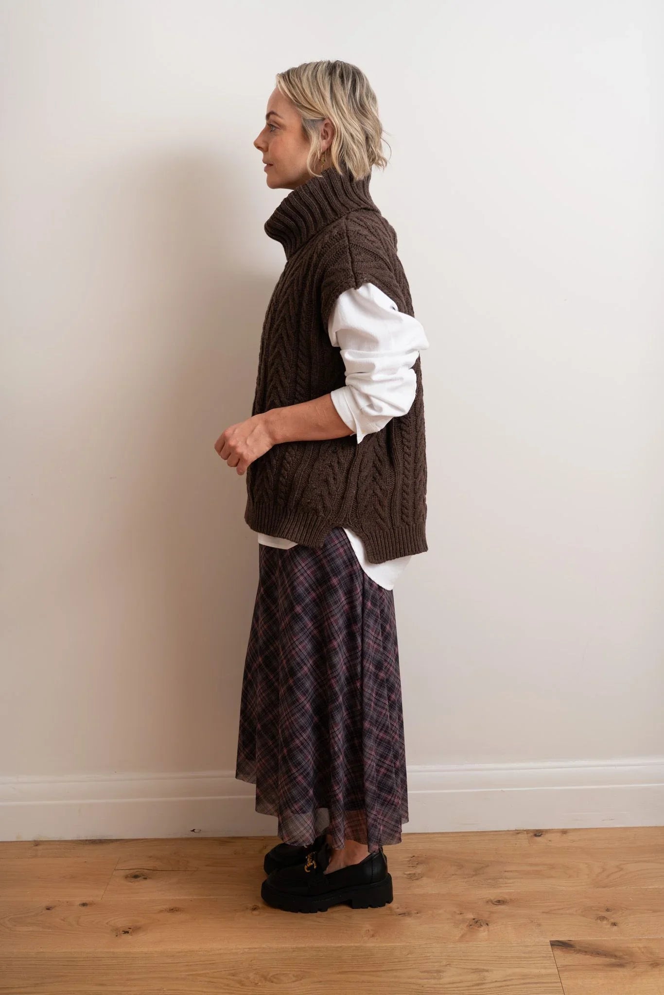 Brown cable knit vest over white shirt with plaid skirt and black loafers
