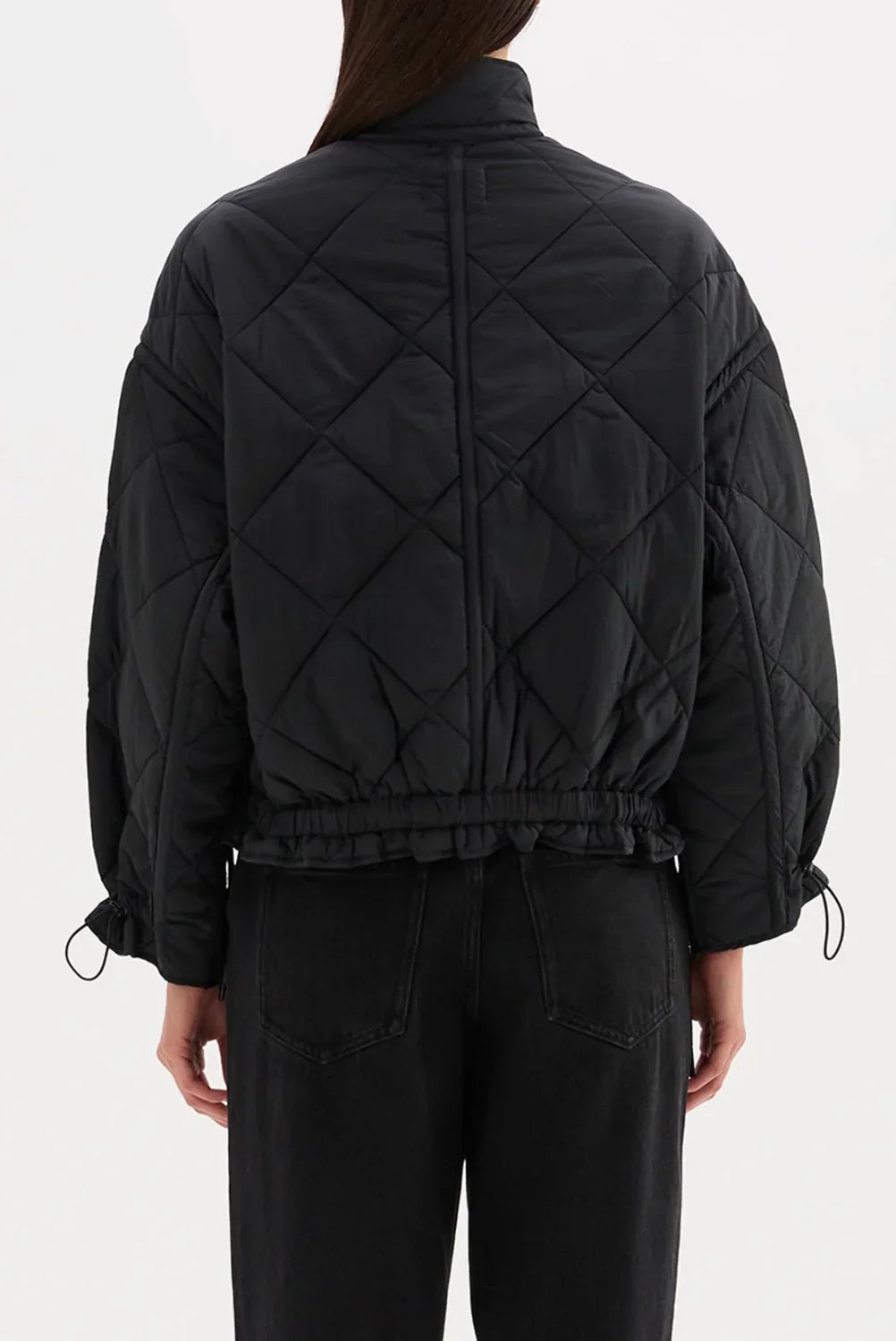 Black quilted puffer jacket with drawstring waist and cuffs, paired with black jeans