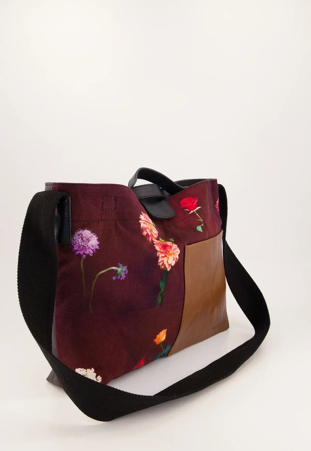 Floral print tote bag with black straps and brown leather accent, ideal for women's fashion