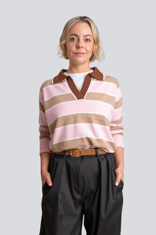 Woman wearing pink and beige striped knit sweater with brown collar and black trousers