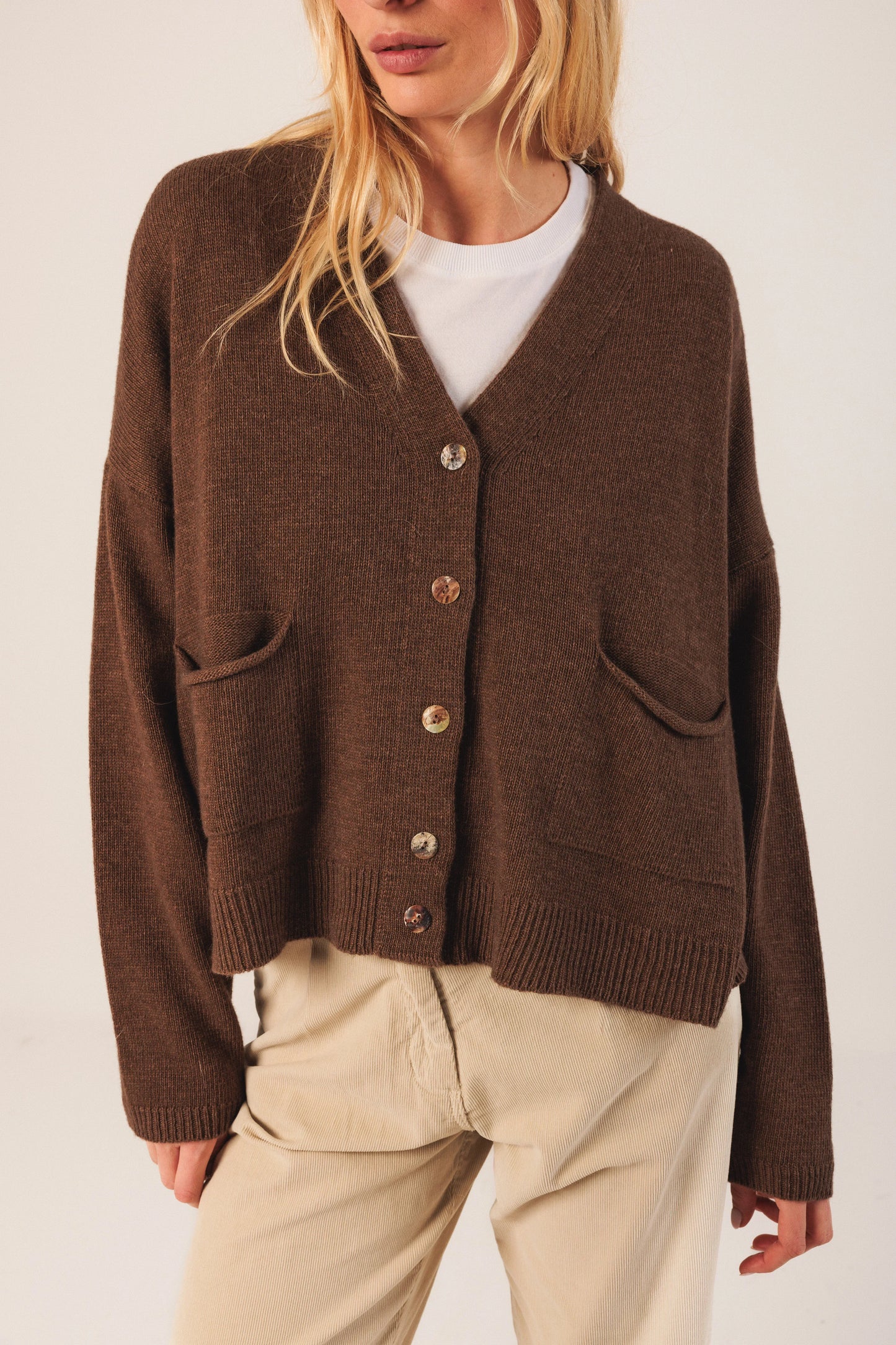 Brown knit cardigan with buttons and pockets, styled with white tee and beige pants for women's fashion
