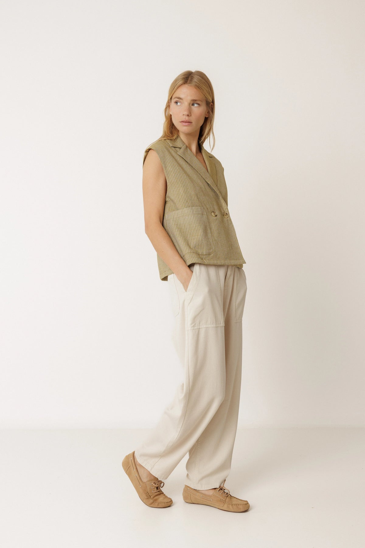 Woman wearing INDI & COLD Pinstripe Tailored Vest in Khaki and wide-leg cream trousers.