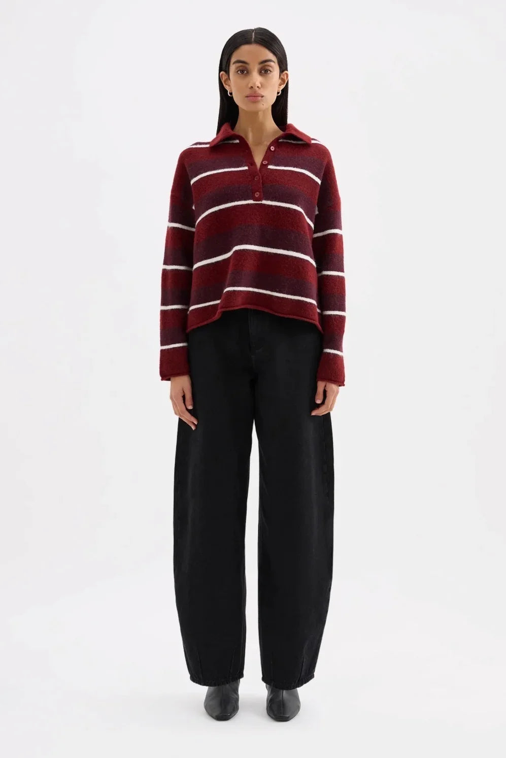 Woman wearing a red and white striped polo sweater and wide-leg black trousers.