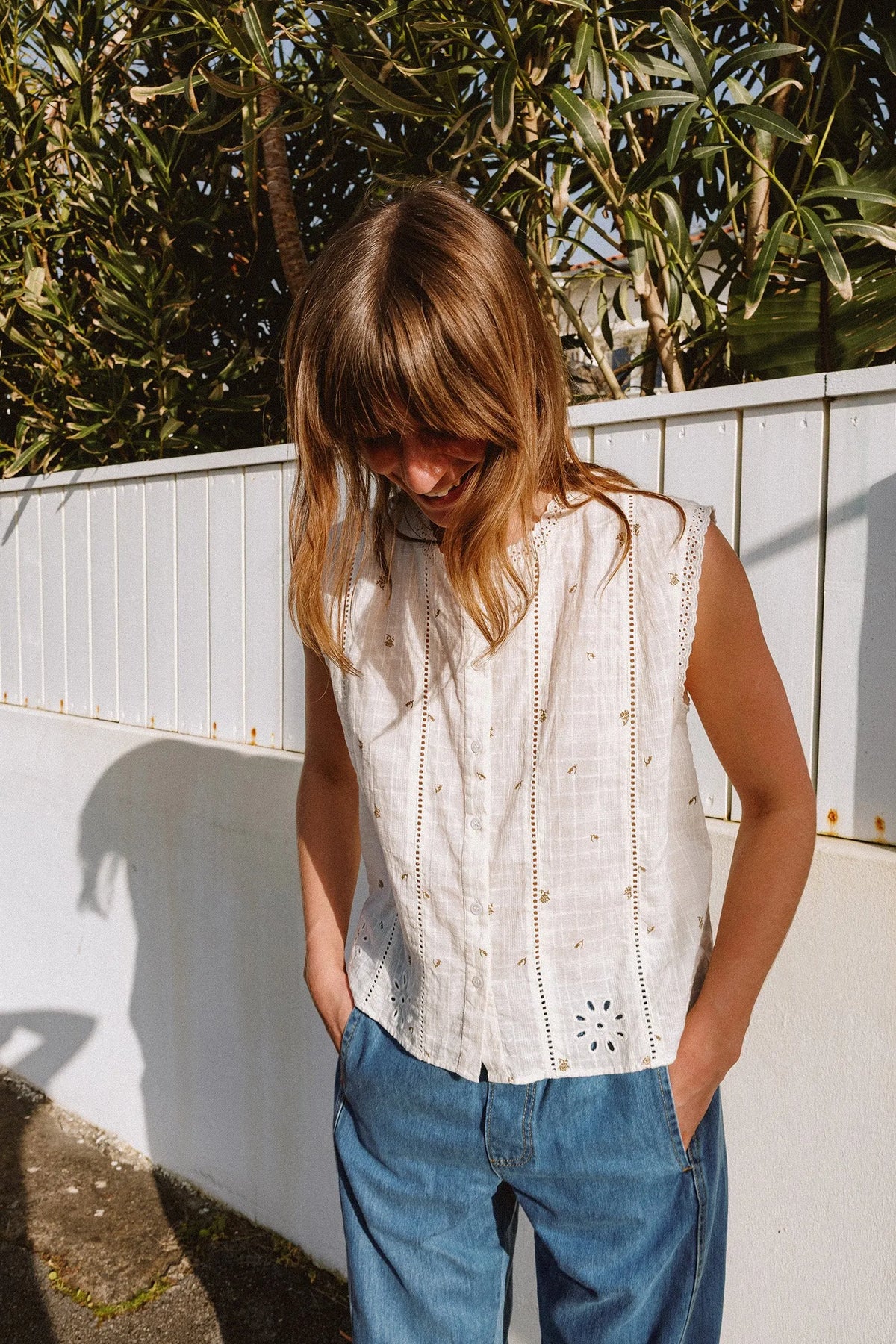 Woman wearing an INDI & COLD Stamp Print Sleeveless Shirt and blue jeans.