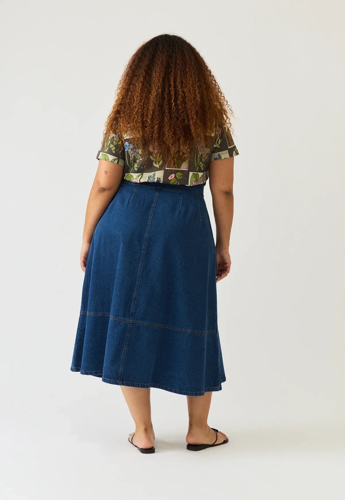 Rear view of a person wearing the NANCYBIRD Aries Denim Skirt in dark wash.