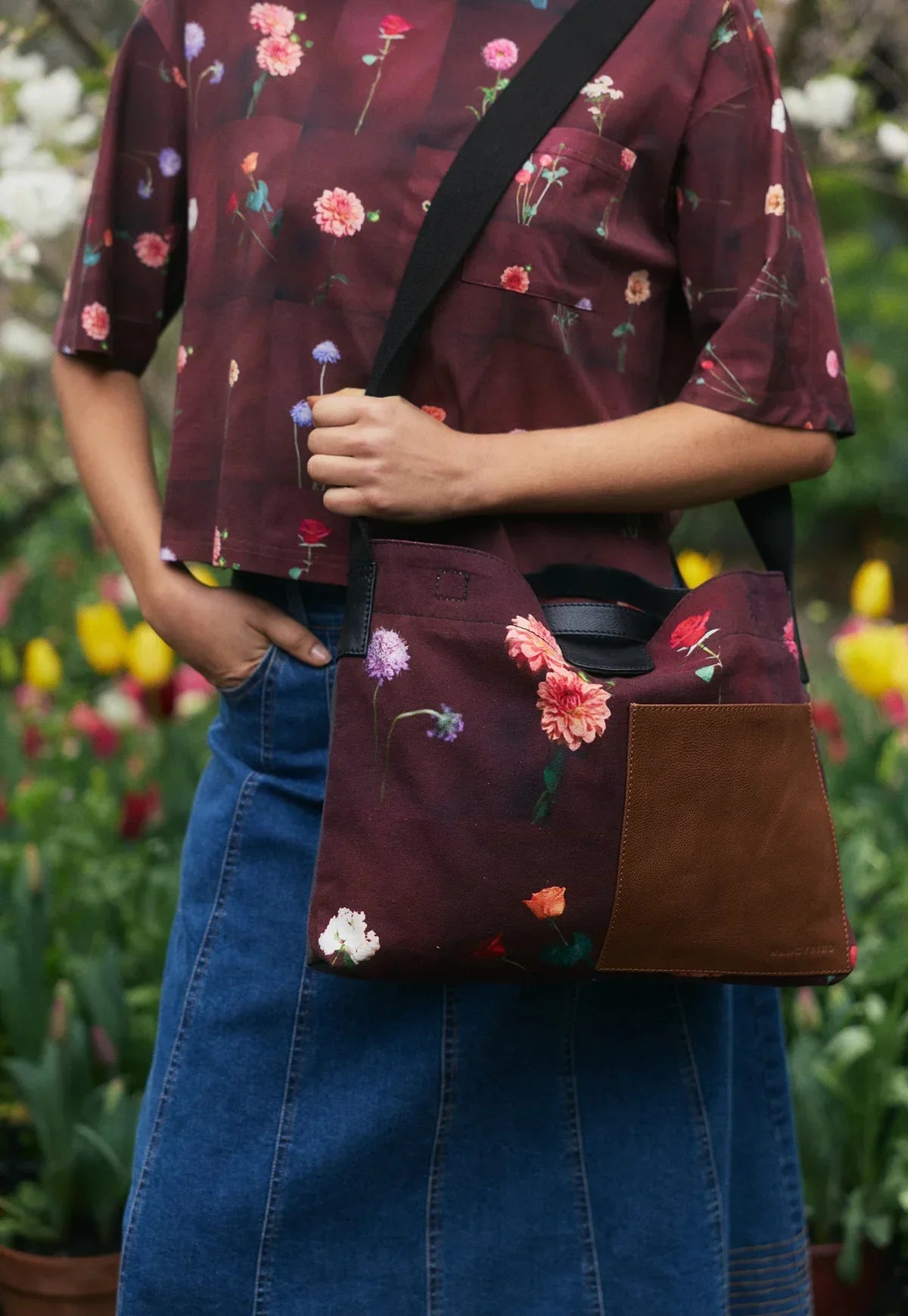Floral print crossbody bag with brown leather patch, paired with denim skirt and floral shirt