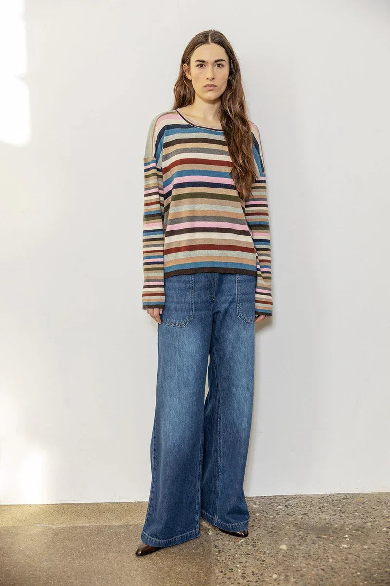 Woman wearing a multicolored striped sweater with wide-leg blue denim jeans indoors