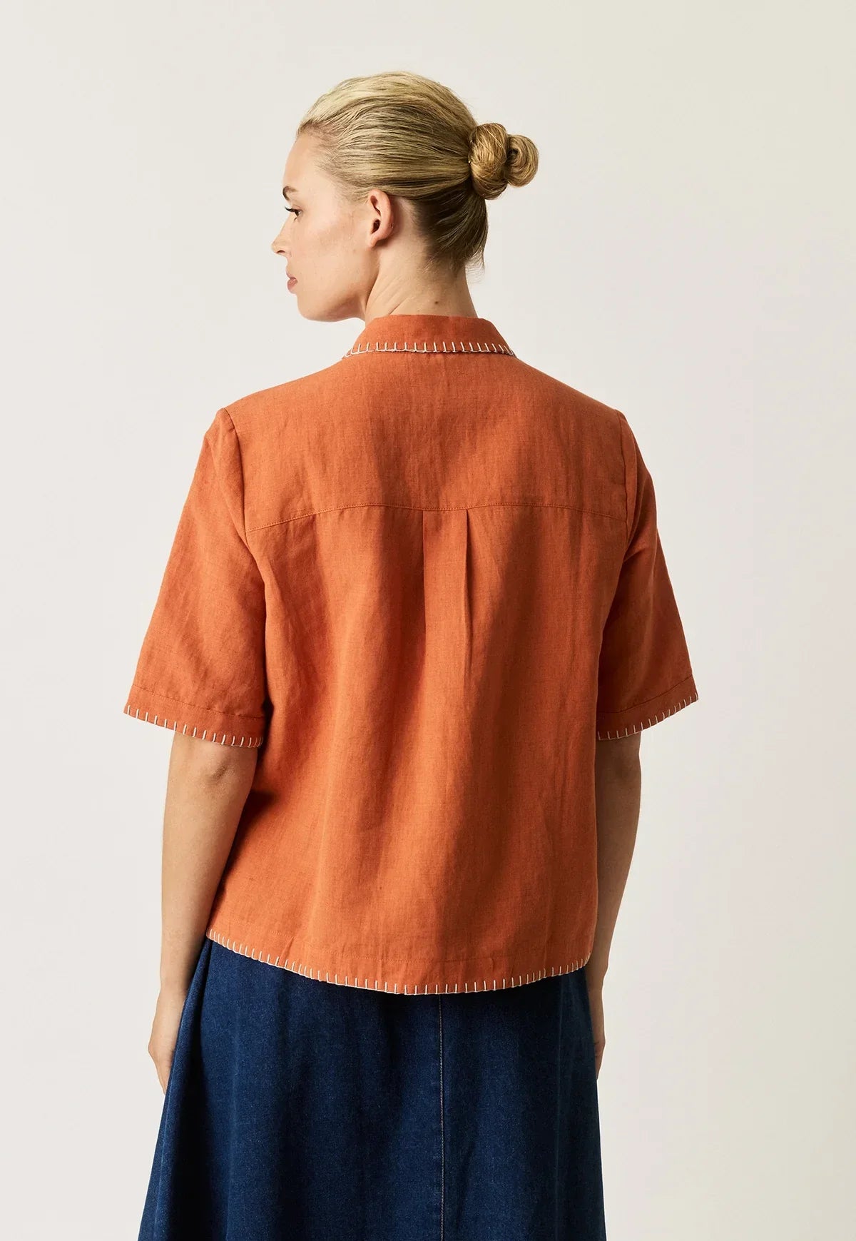 Back view of a woman wearing a NANCYBIRD Summer Shirt in Blossom Appliqué and a navy skirt.