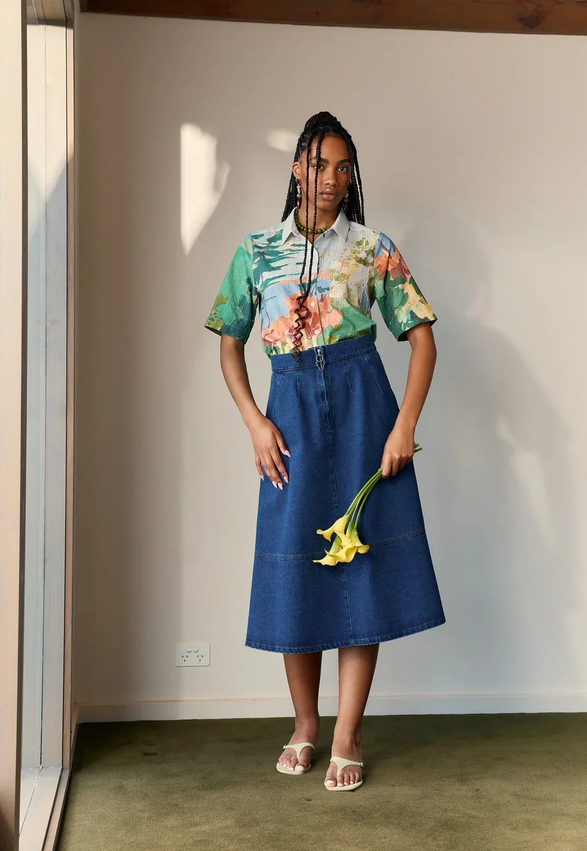 Model wearing a NANCYBIRD Aries Denim Skirt in dark wash with a floral print shirt.