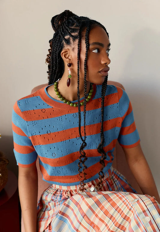 Woman wearing NANCYBIRD Rana Knit Tee in Terracotta Stripe with a matching plaid skirt.