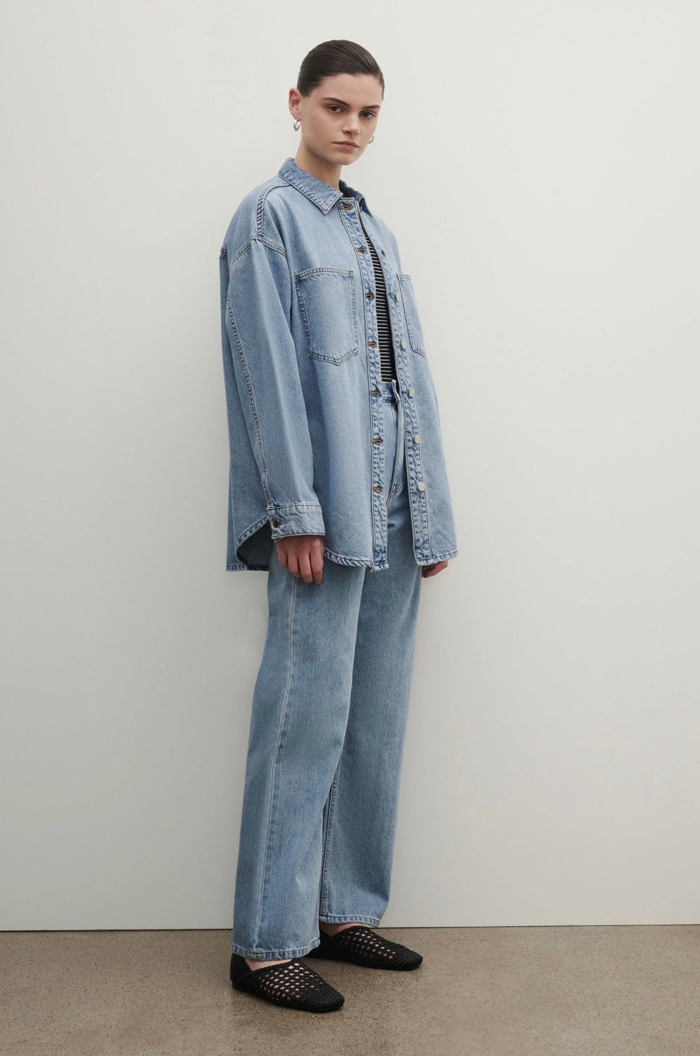 Woman in oversized denim shirt and wide-leg jeans with black woven flats