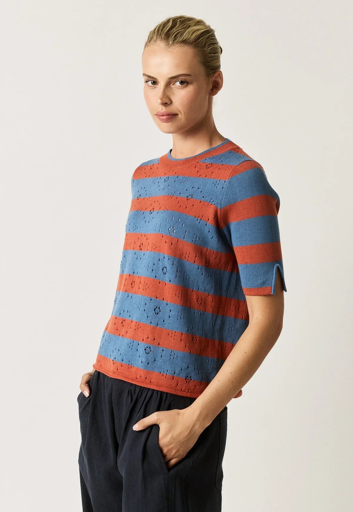 Woman wearing NANCYBIRD Rana Knit Tee in terracotta and blue stripes with navy trousers.