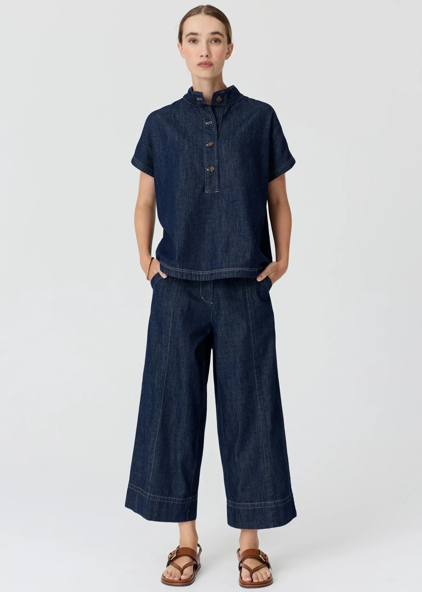 Woman wearing a dark wash denim short-sleeved top and wide-leg trousers set.