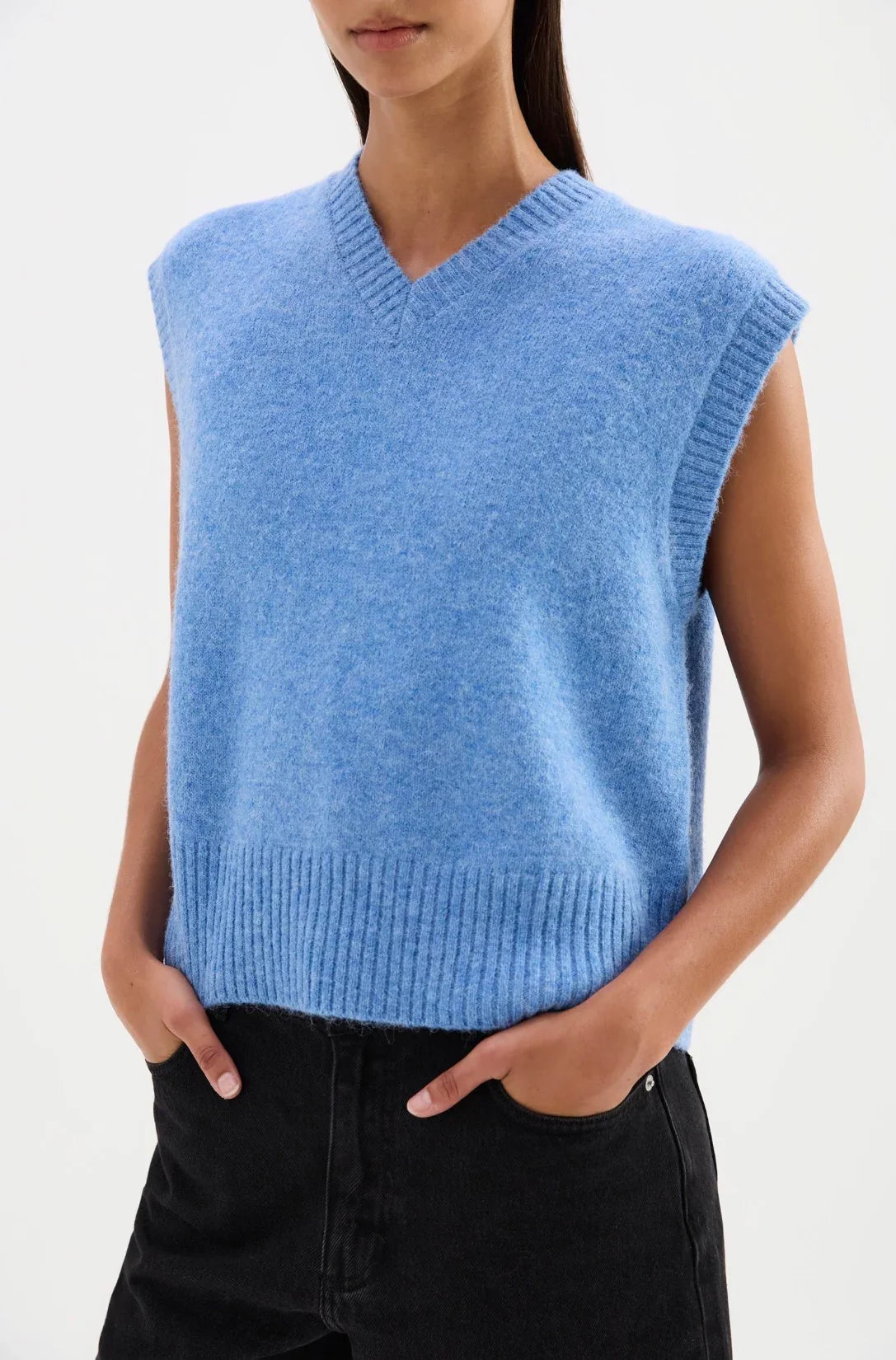 Woman wearing a soft blue knit sleeveless sweater vest with black pants