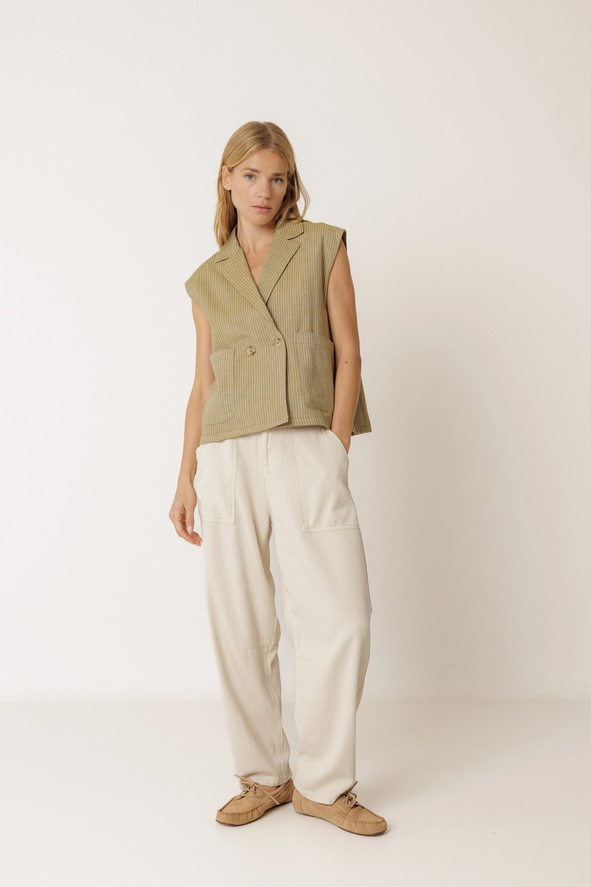 Woman wearing an INDI & COLD Pinstripe Tailored Vest in Khaki and cream trousers.