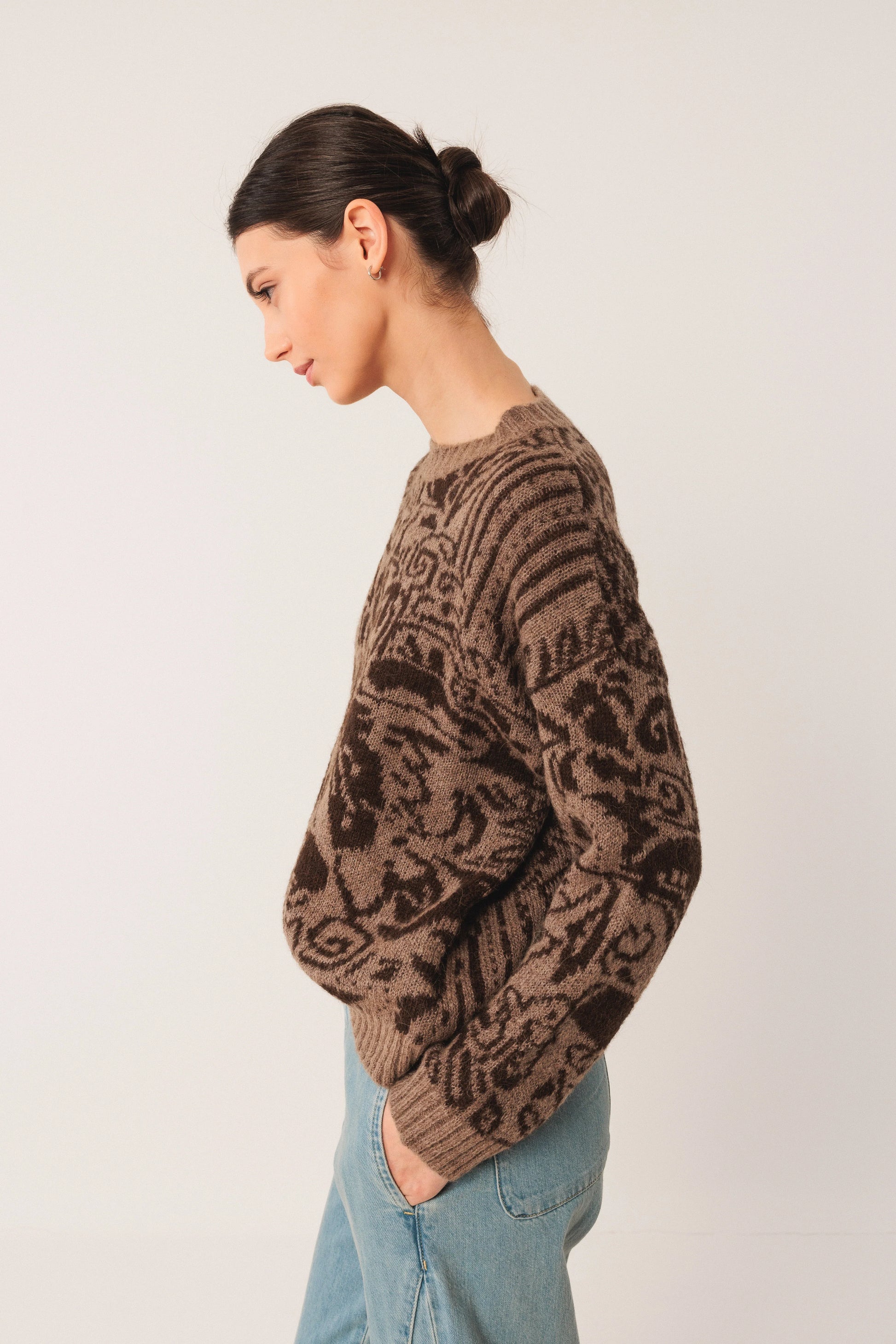Brown patterned knit sweater with relaxed fit, paired with light blue jeans for casual style