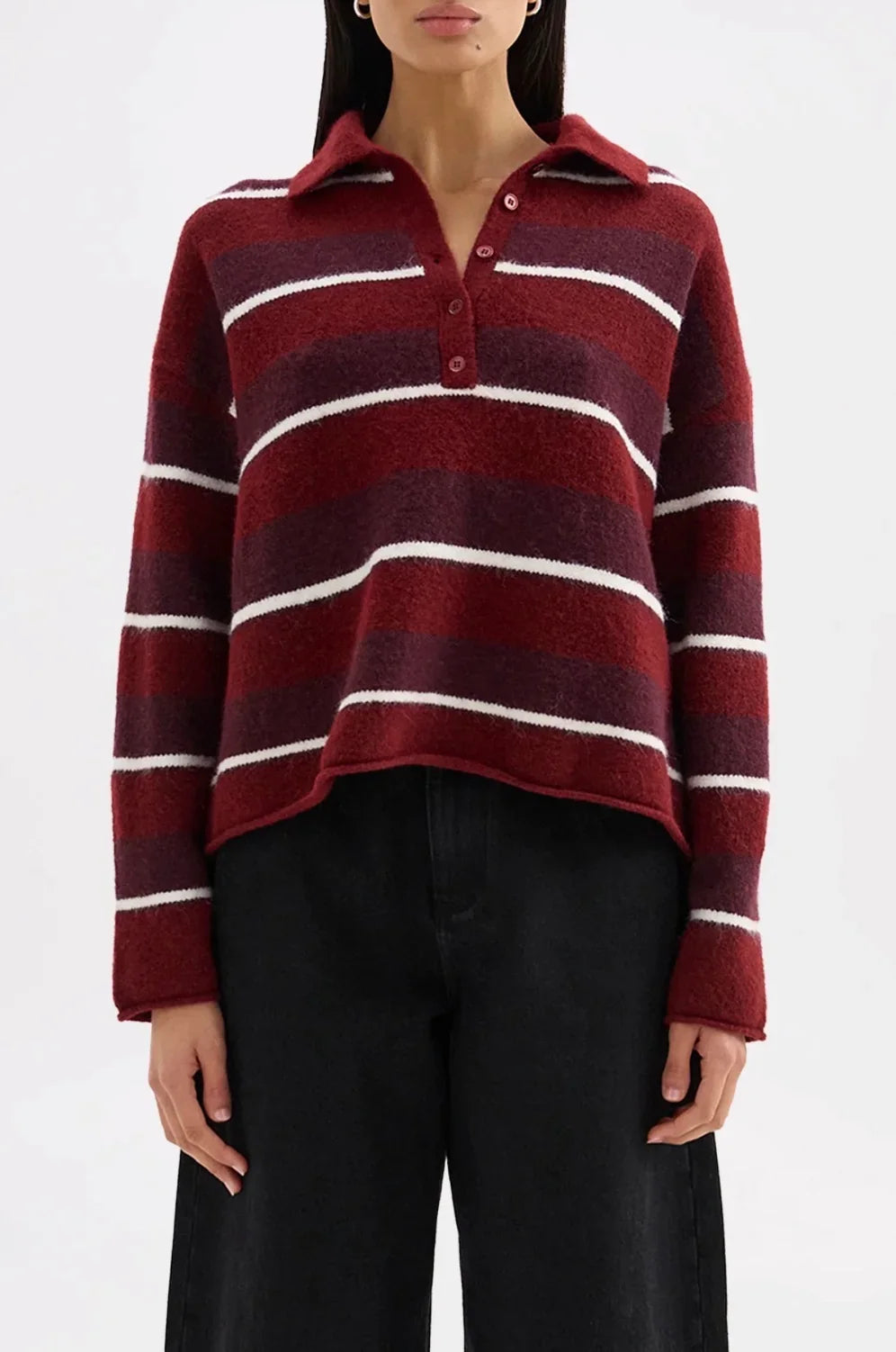 Woman wearing a maroon and white striped long-sleeve knit polo shirt and black trousers.