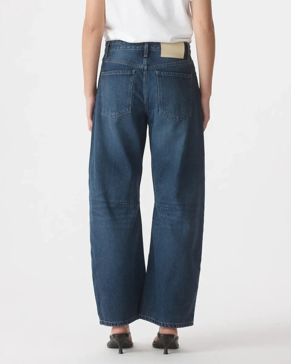 Back view of wide-leg blue denim jeans with high waist and rear pockets, paired with heels