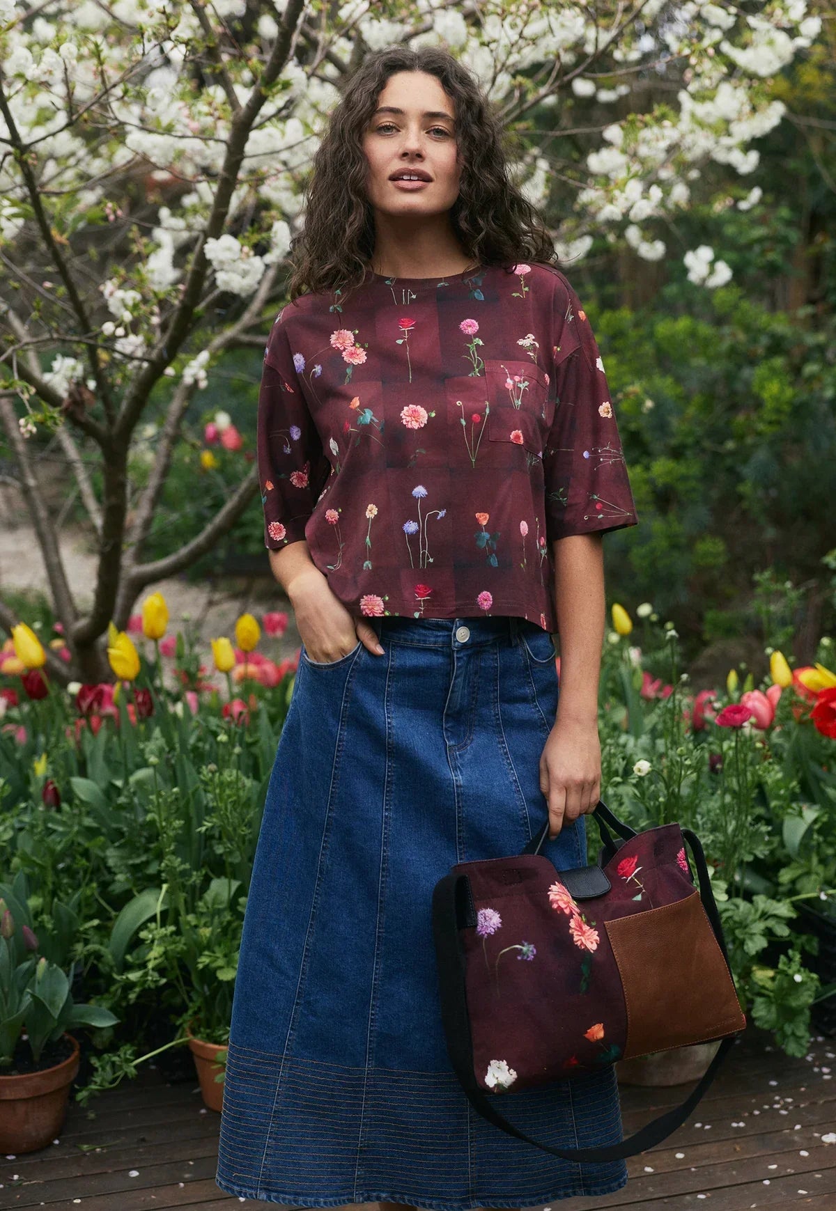 Floral print burgundy top with denim skirt and matching tote bag in garden setting