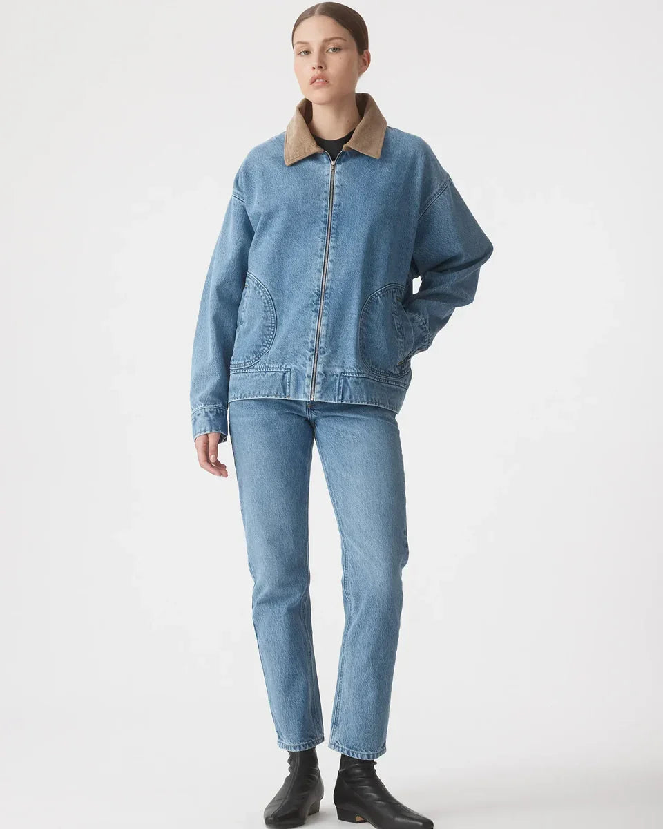 Woman wearing blue denim jacket with tan collar, matching jeans, and black ankle boots