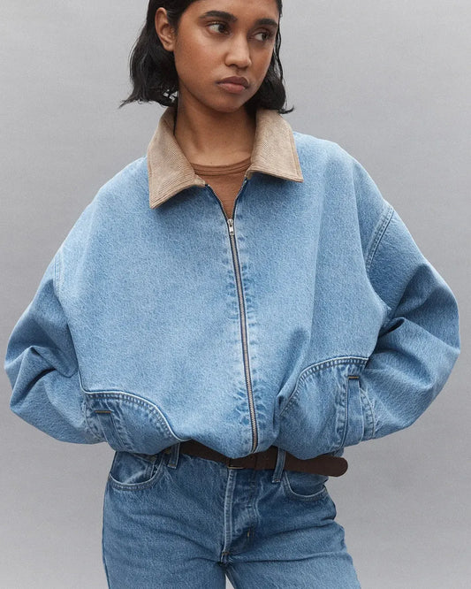 Woman wearing oversized denim jacket with tan corduroy collar and blue jeans