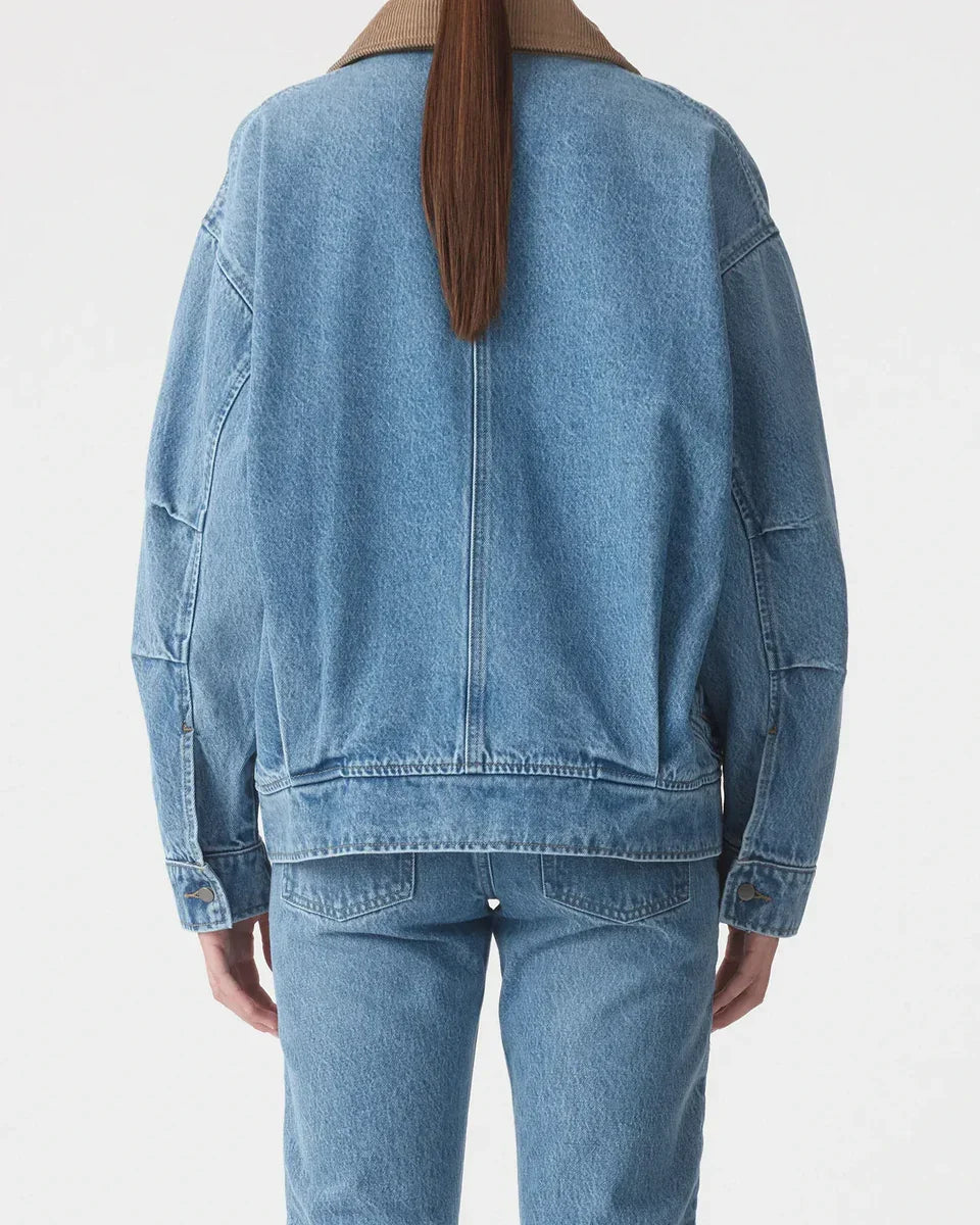 Back view of woman wearing light blue denim jacket and jeans with brown collar
