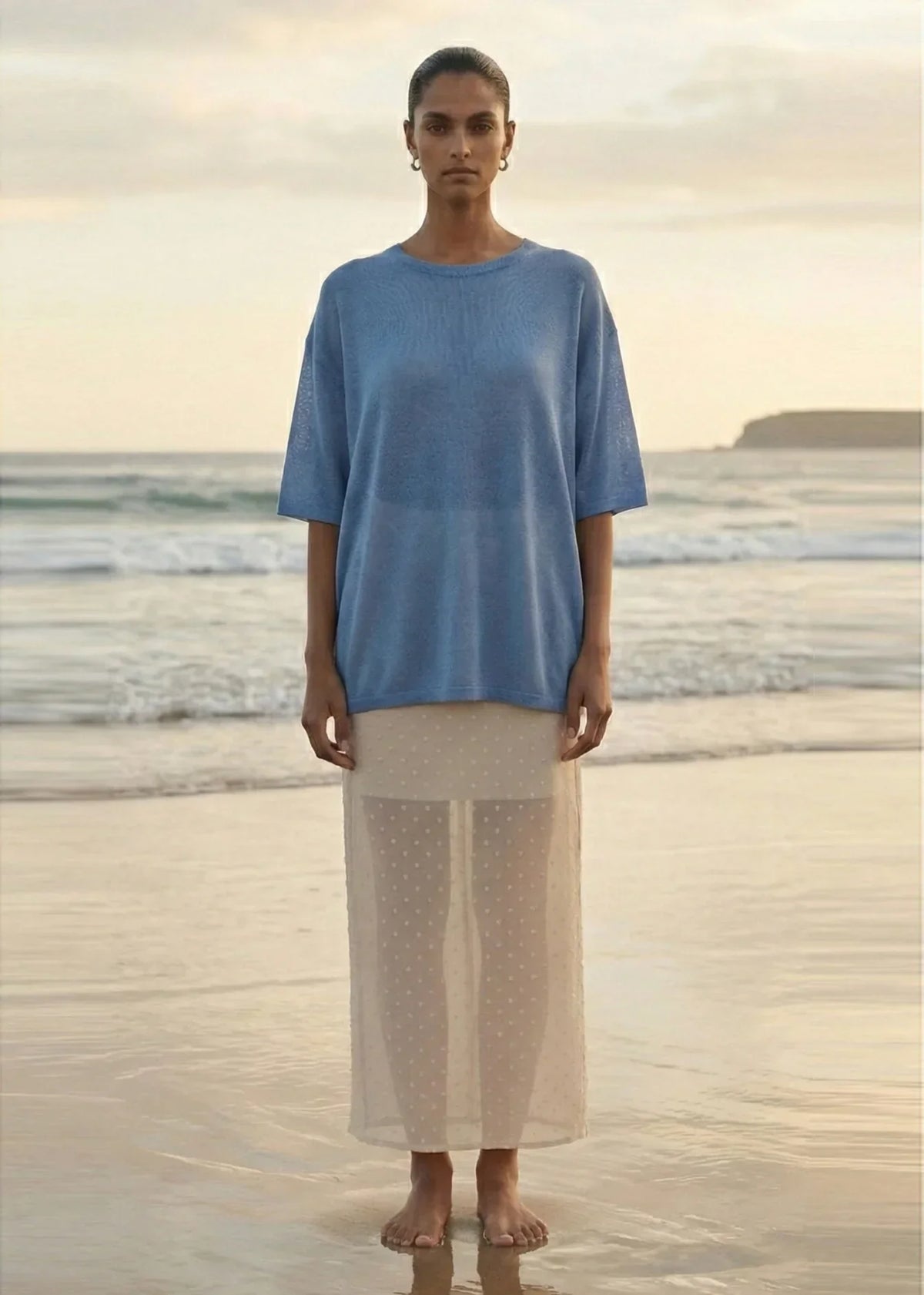 Woman wearing STAPLE THE LABEL Etoile Layered Midi Skirt in Cream Spot on a beach.