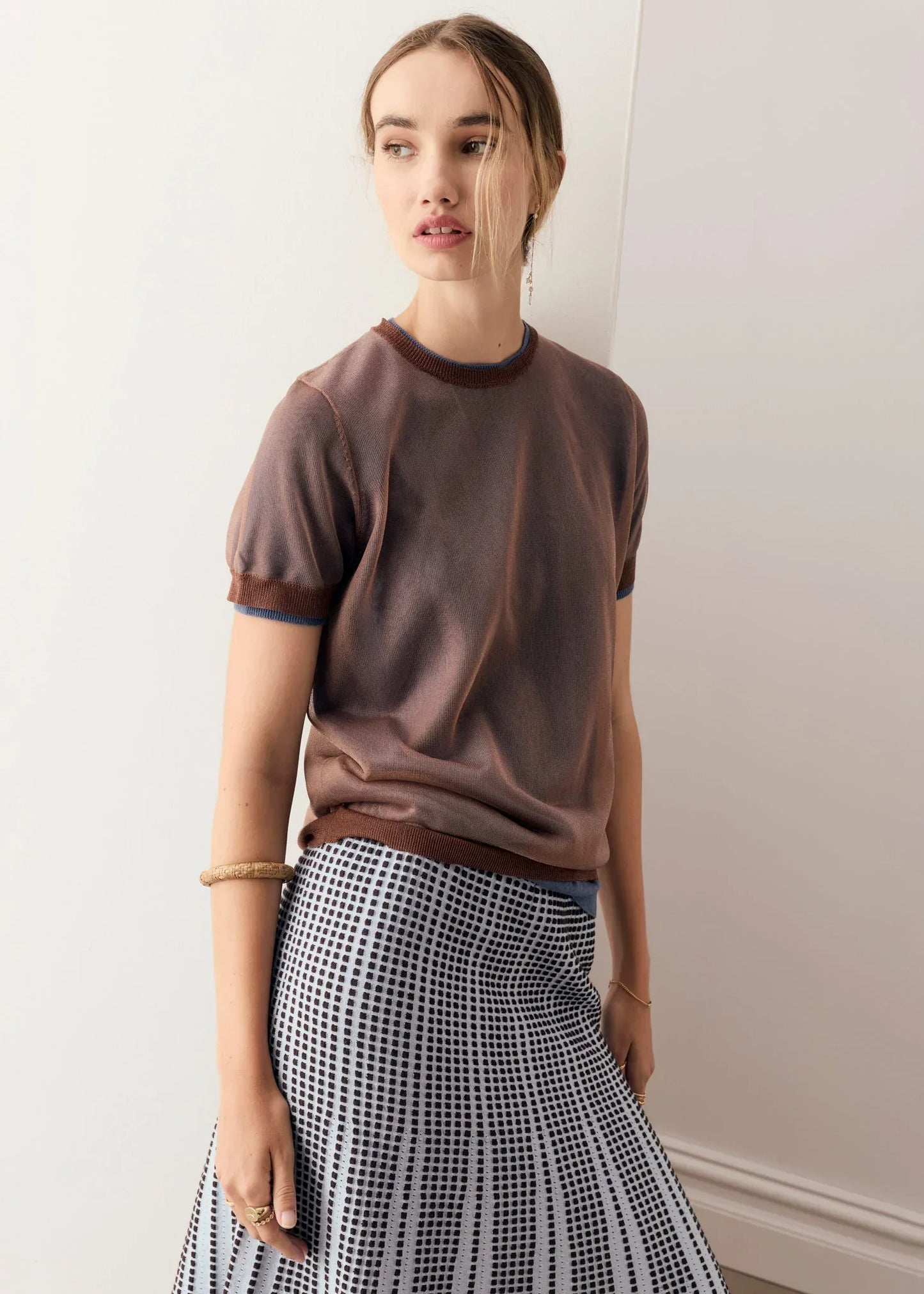 Woman wearing the POL Kaspar Layered Tee, a brown short-sleeved t-shirt and a patterned grey and black skirt.
