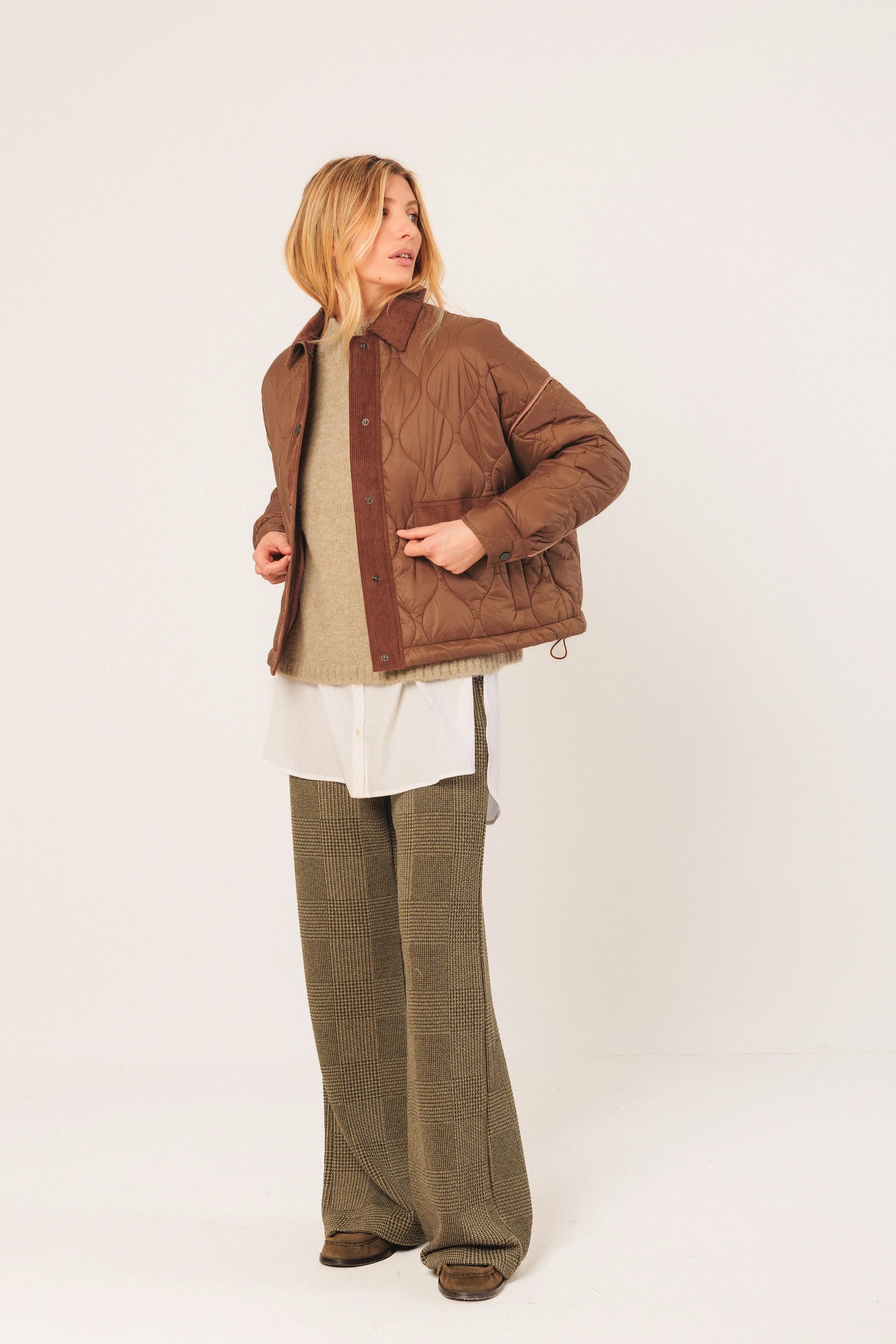Brown quilted jacket with corduroy trim, paired with wide-leg pants and layered top
