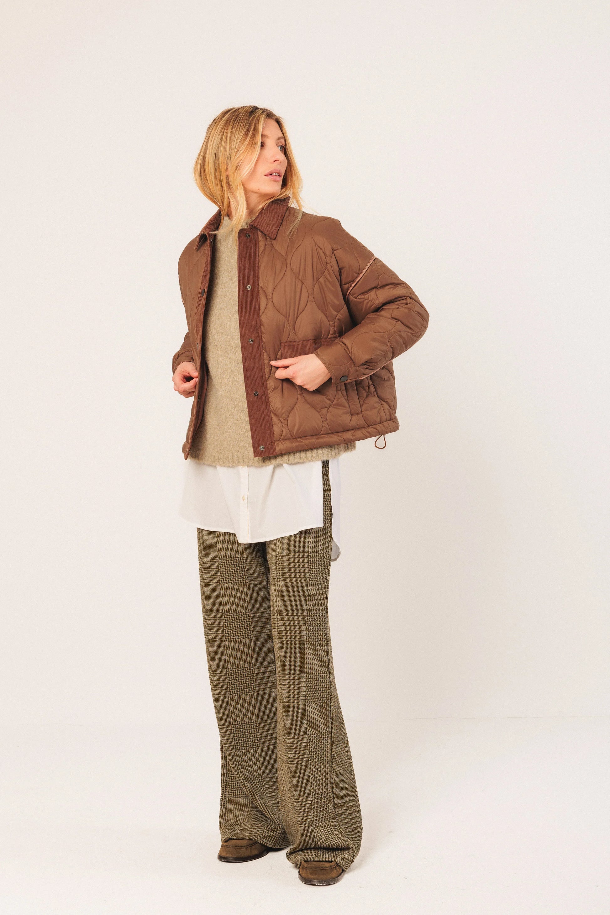 Brown quilted jacket with corduroy trim, paired with wide-leg pants and layered top
