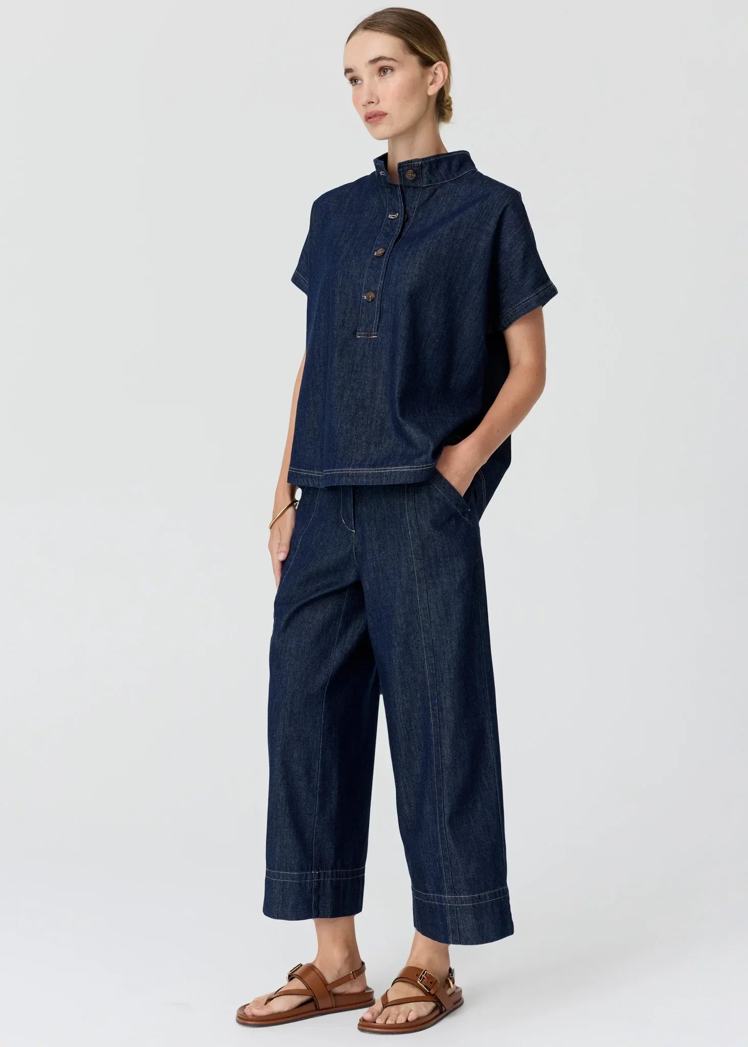Woman wearing a dark wash denim short-sleeve shirt and matching wide-leg trousers.