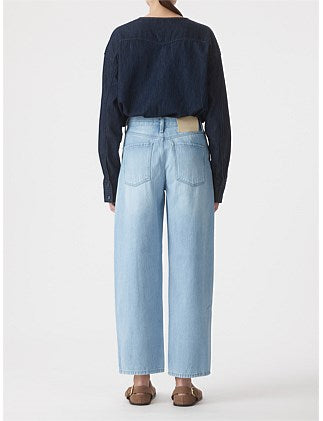 Person wearing a navy shirt and light blue jeans on a white background